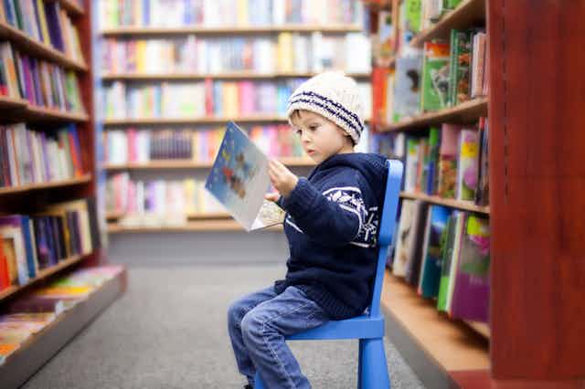 boy seated in library reading a book