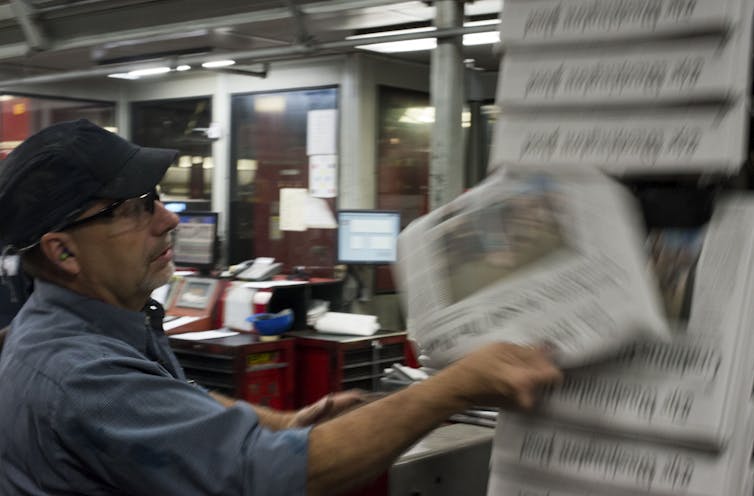 An inspector checks a copy of the Washington Post for quality control