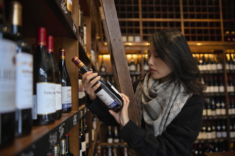 A woman holds a bottle of wine in a bottle shop in China