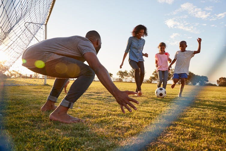 Father and children playing football together