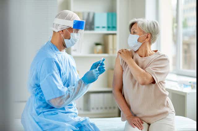 A health-care worker administers a vaccine to a woman.