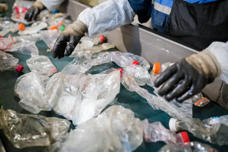 A production line with plastic bottles and other plastic waste being sorted on a factory line.