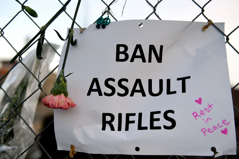 A sign on a fence in Boulder that says "Ban assault rifles"