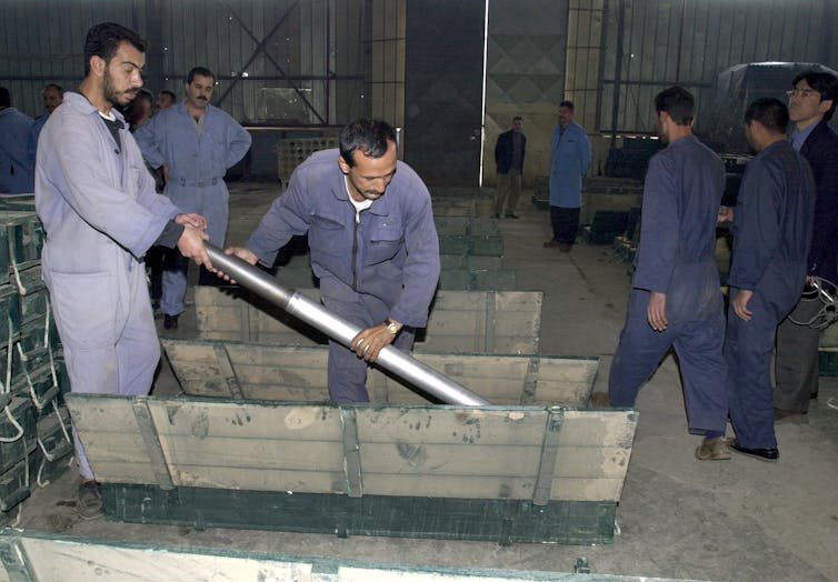 Two Iraqi workers put a missile in a box at the Dhu-Alfhiqar factory, December 2002 during a visit to the Nasr military industries complex in al-Taji, 50kms north-west of Baghdad, by UN arms experts.