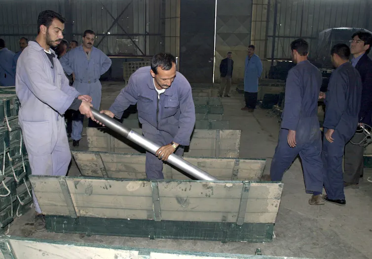 Two Iraqi workers put a missile in a box at the Dhu-Alfhiqar factory, December 2002 during a visit to the Nasr military industries complex in al-Taji, 50kms north-west of Baghdad, by UN arms experts.