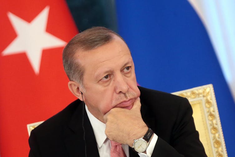 President Erdogan in front of some flags looking pensive
