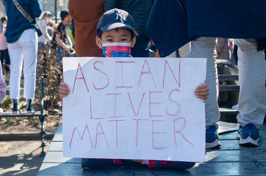 As child holds a 'Asian lives matter' sign
