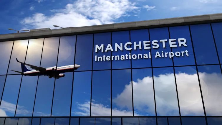 Manchester airport terminal with plane reflected in glass