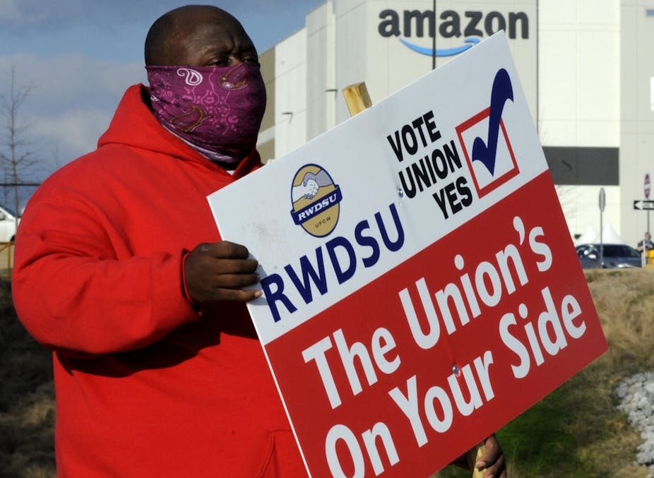 A man holds a sign supporting a union outside an Amazon facility in Bessemer, Alabama