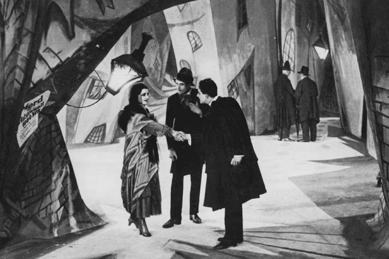 Black and white still of three people talking in film The Cabinet of Dr Calgari.