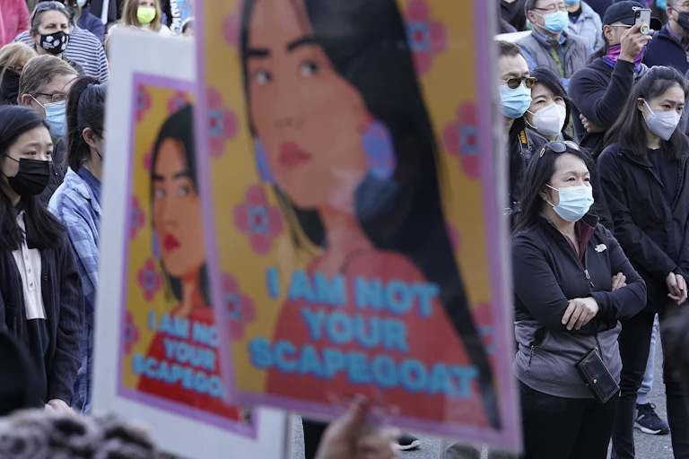 A poster that says "I am not your Scapegoat" is held up at a protest.