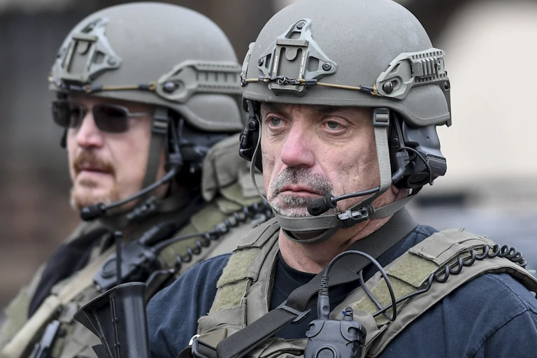 Two police officers wearing protective gear and looking sad.