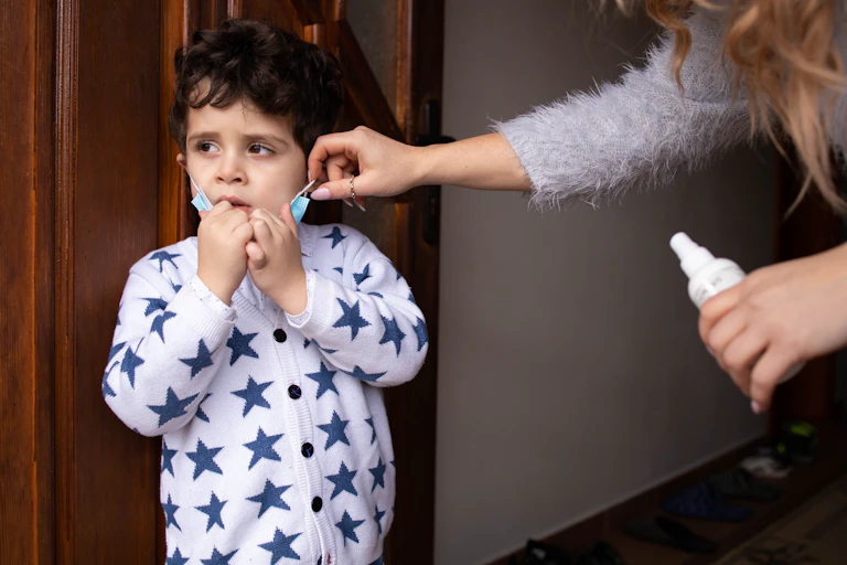 A mother helps a boy with a face mask.