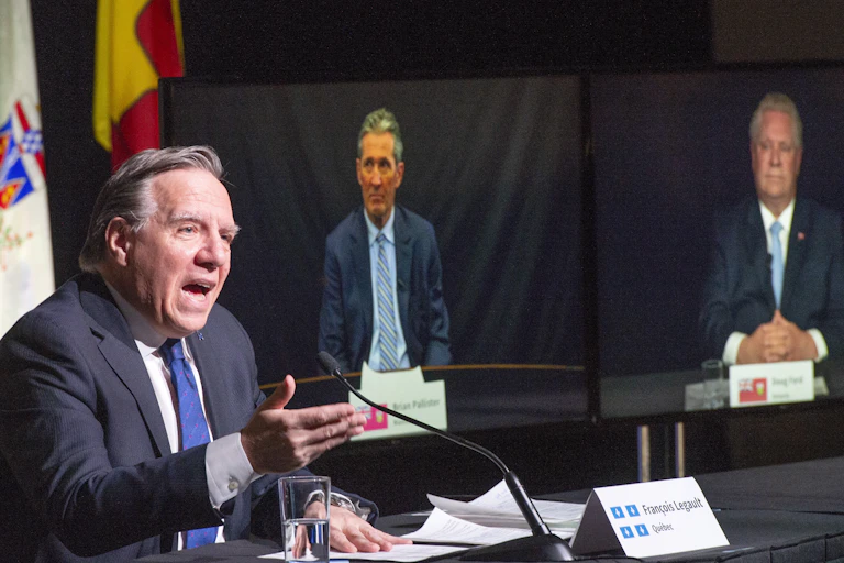 QuébecFrancois Legault speaks as Brian Pallister and Doug Ford appear on video screens behind him.