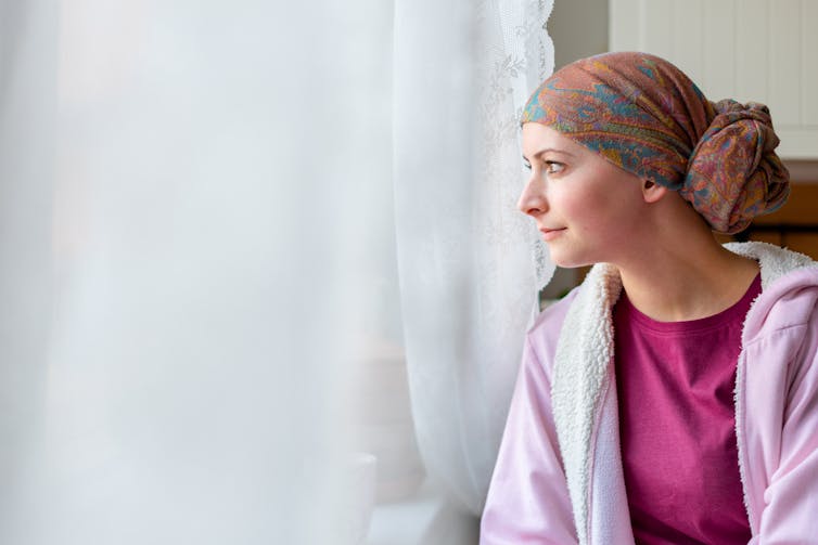 A woman wearing a head scarf looks out the window.