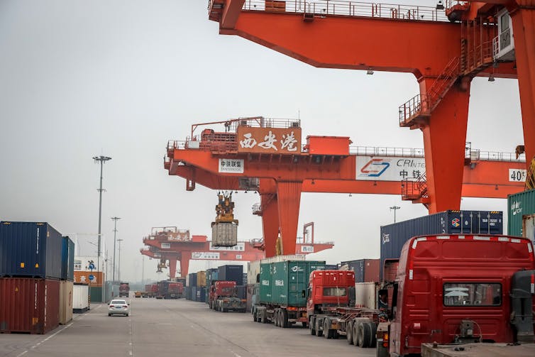 Chinese trucks parked next to containers and loading cranes
