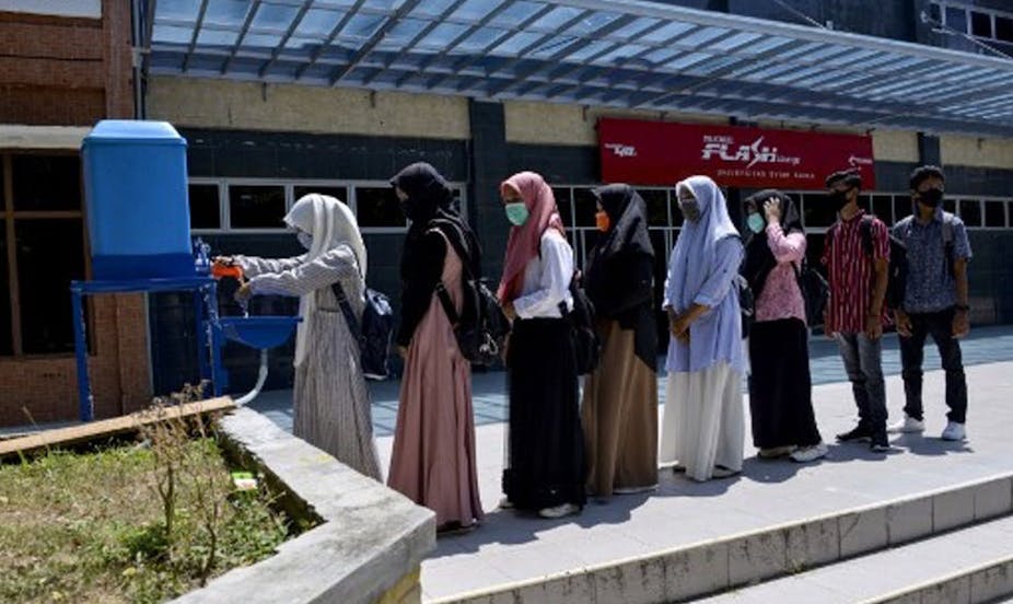 Students wash their hands amid concerns over the Covid-19 coronavirus before taking a college university exam in Banda Aceh. 