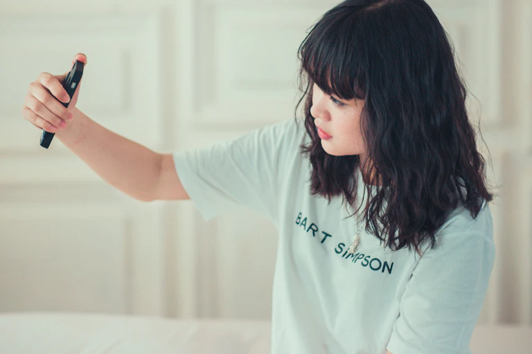 A woman holds up a smartphone with her right hand to take a selfie