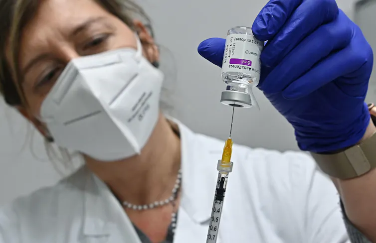 A woman wearing a face mask prepares a vaccine.