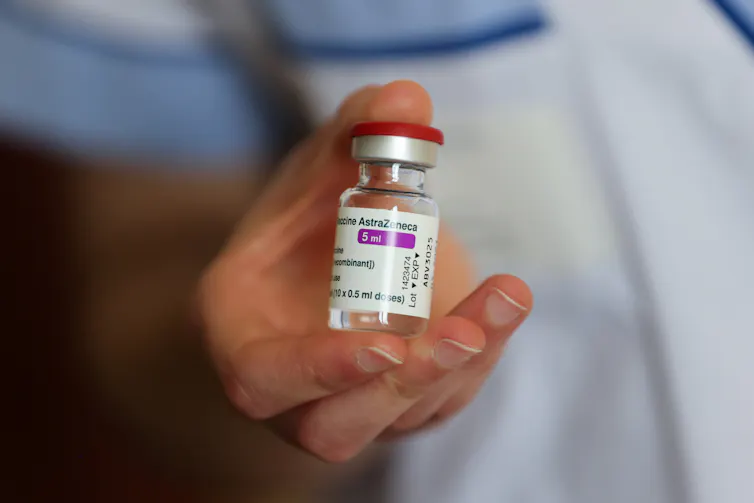 A hand holding a vial of AstraZeneca's COVID-19 vaccine.