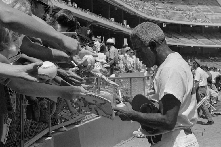 Jackie Robinson signing autographs.