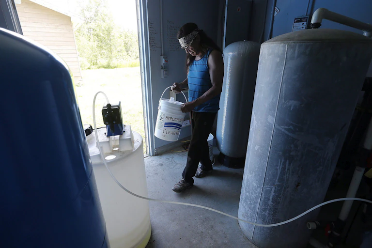 Man stands carrying a bucket of chlorine