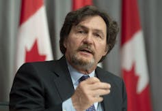 A man sitting in front of a row of Canadian flags