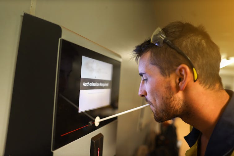 A man does a breath test for alcohol before entering a mine site.