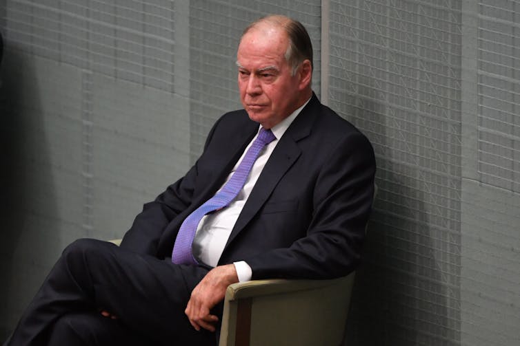 Man in suit and tie listening to question time in parliament