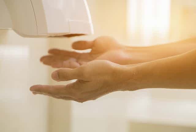 Close up of hands under bathroom hand dryer