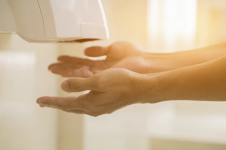 Close up of hands under bathroom hand dryer