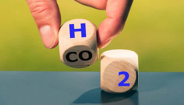 hand holds die with letters H CO and 2 visible