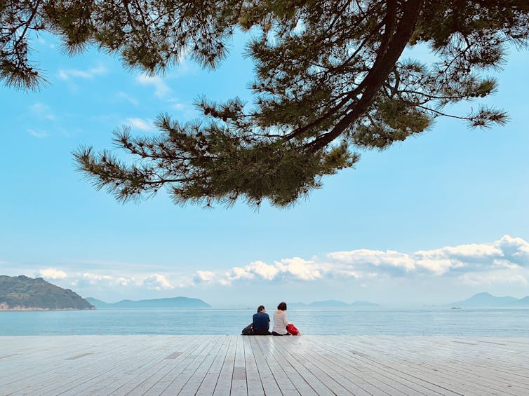 Couple sit on deck with Japan sea on horizon.