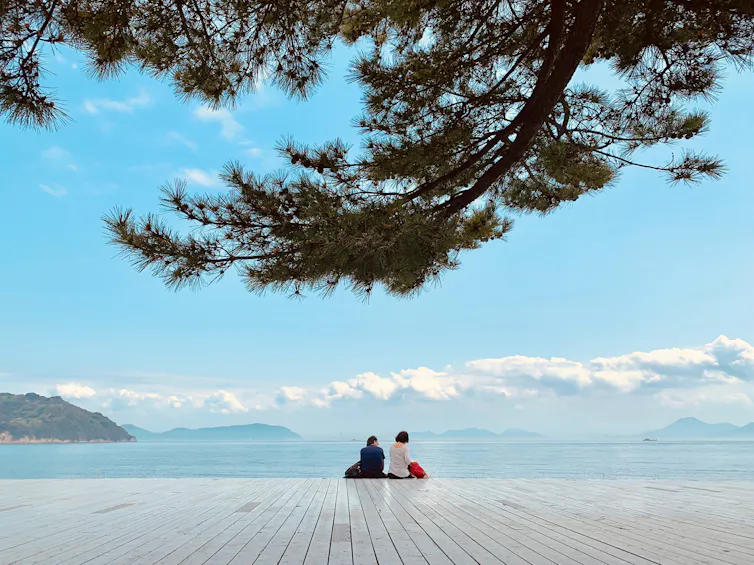 Couple sit on deck with Japan sea on horizon.
