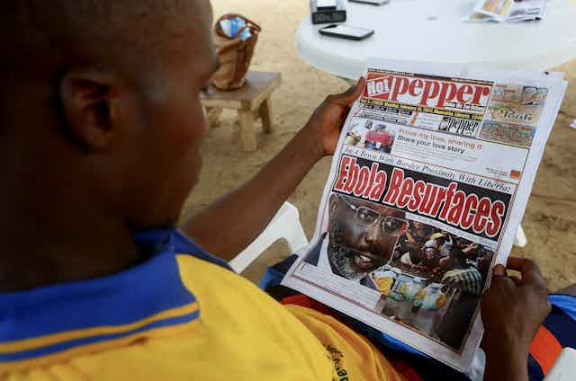 A Liberian man reads a newspaper reporting on the Ebola outbreak in neighbouring Guinea at a sidewalk news stand in Monrovia, Liberia. 