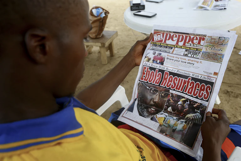 A Liberian man reads a newspaper reporting on the Ebola outbreak in neighbouring Guinea at a sidewalk news stand in Monrovia, Liberia.