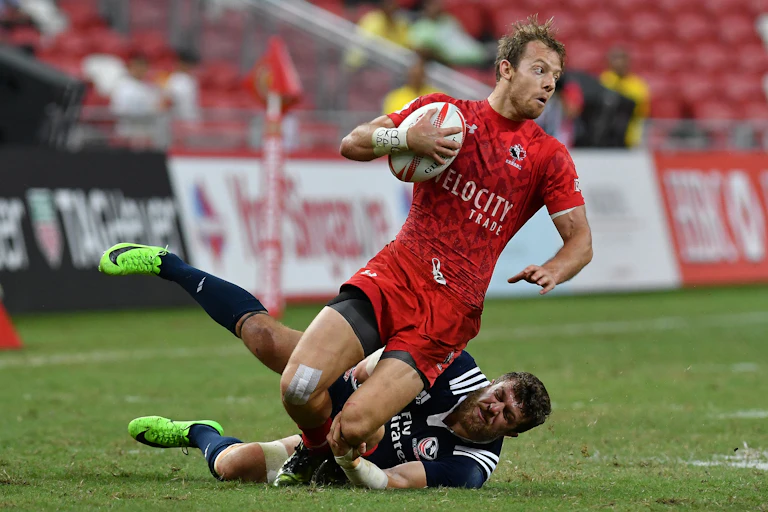 A rugby player tackles a player from the other team who has the ball.