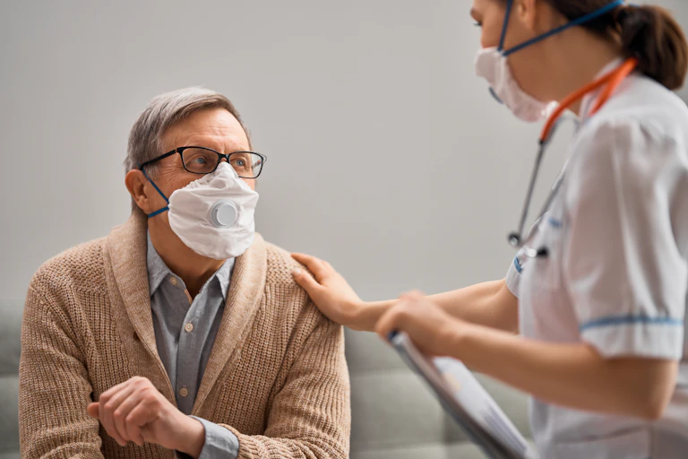 Doctor and senior man wearing facemasks.