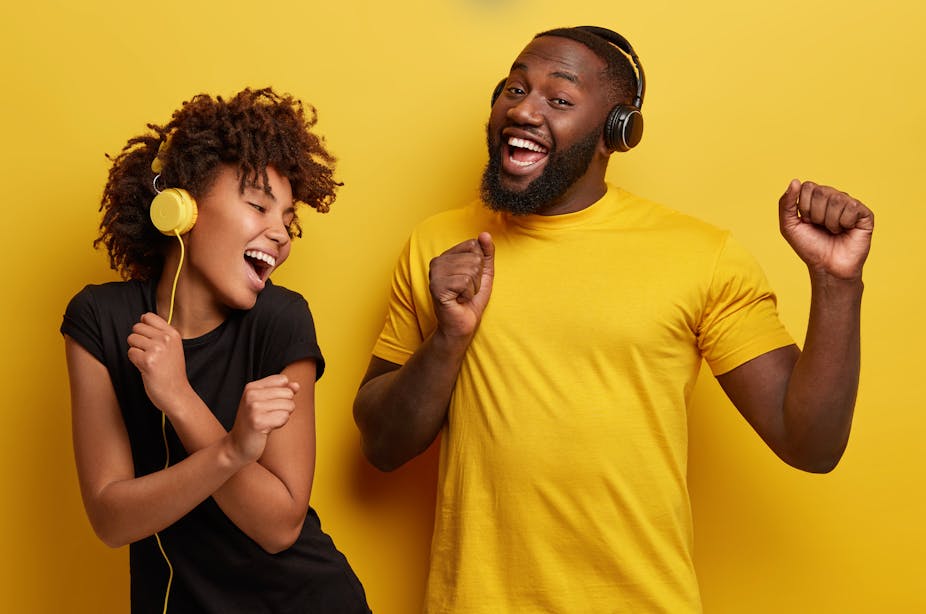 Two people wearing headphones and smiling.
