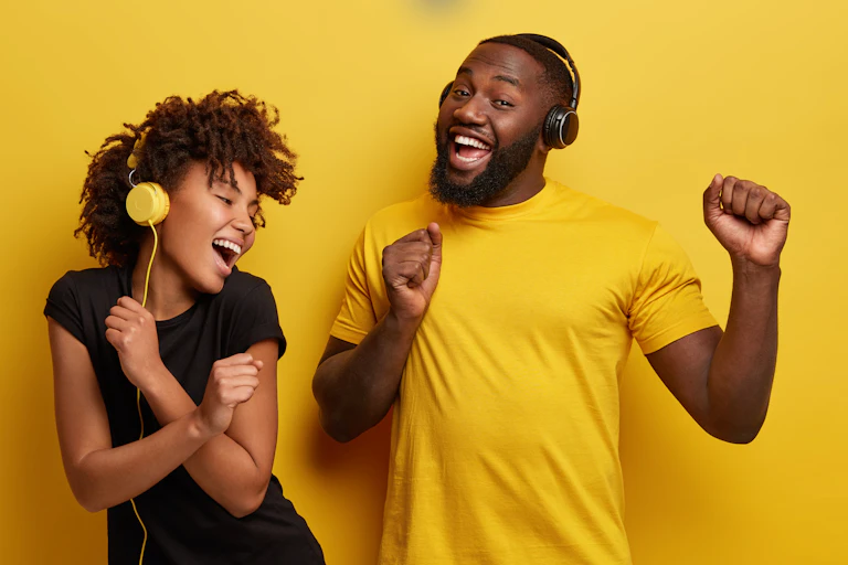 Two people wearing headphones and smiling.