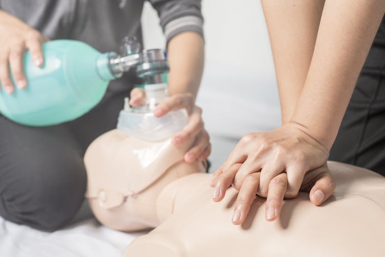 Hand pressing down on the chest of a medical dummy.