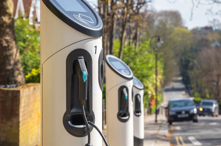 A row of three electric vehicle charging stations at the side of a road in London