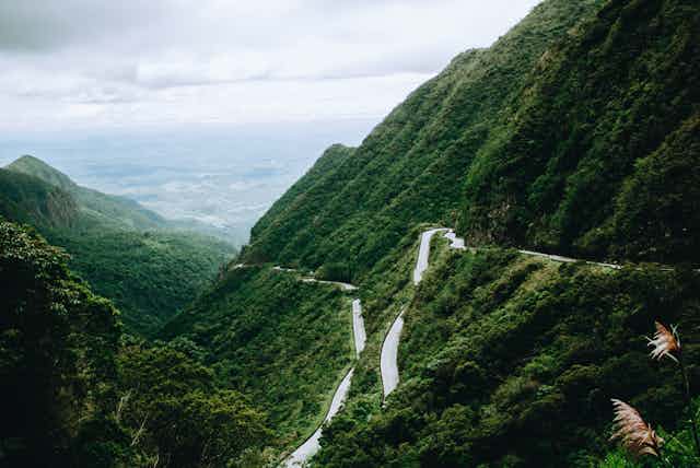 A road winds alongside green mountains