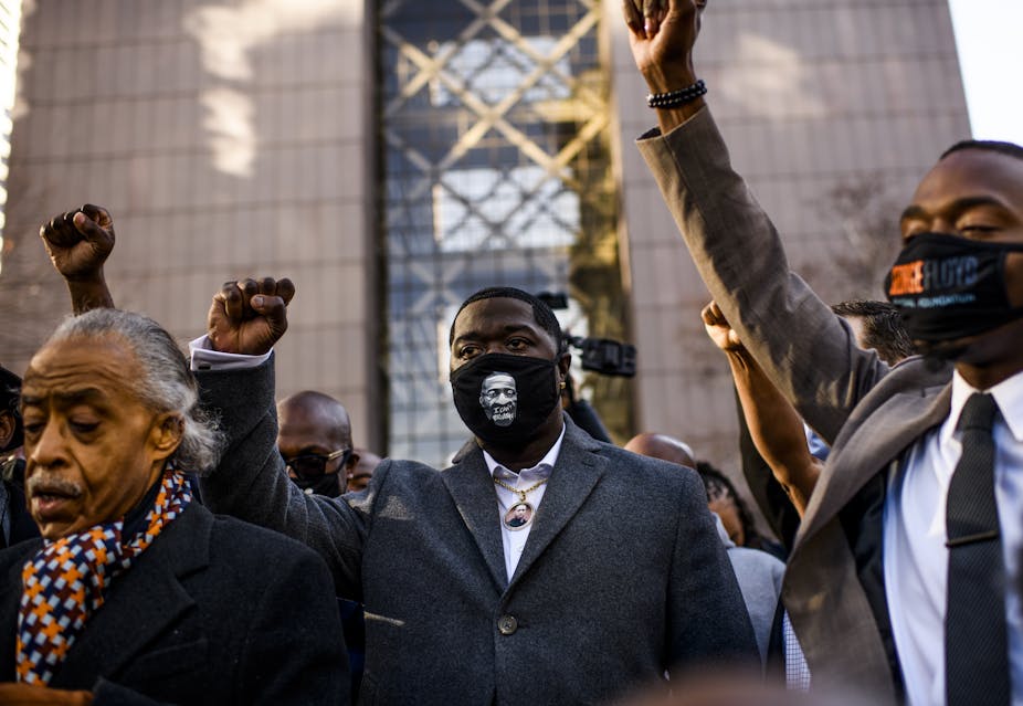 Black men with raised fists outside a court building