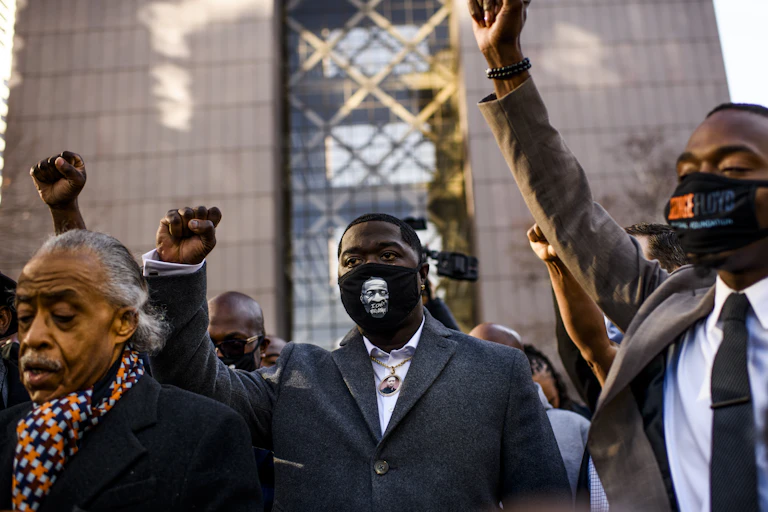 Black men with raised fists outside a court building
