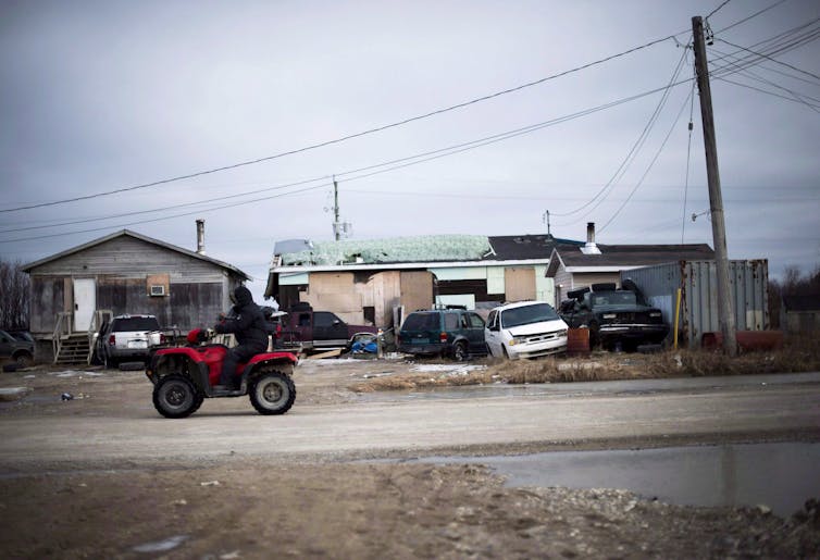 A man rides his ATV through a First Nations community