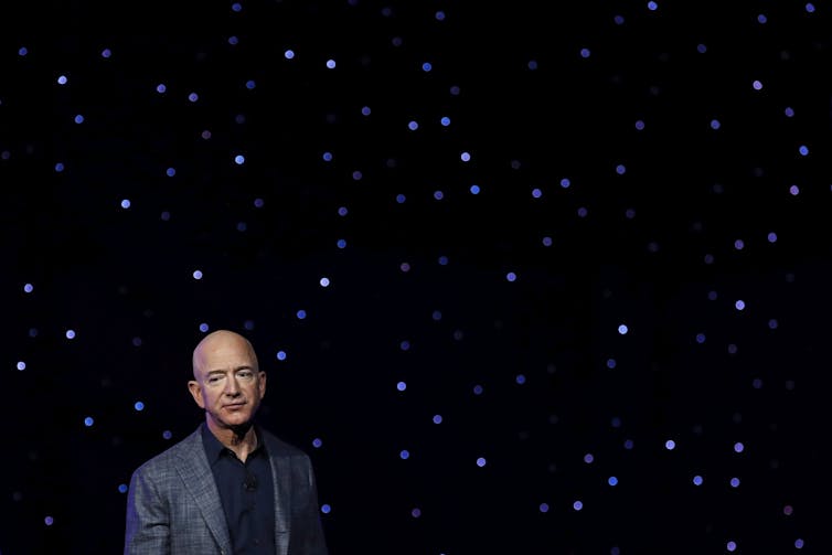 Jeff Bezos stands in front of a starlight backdrop.