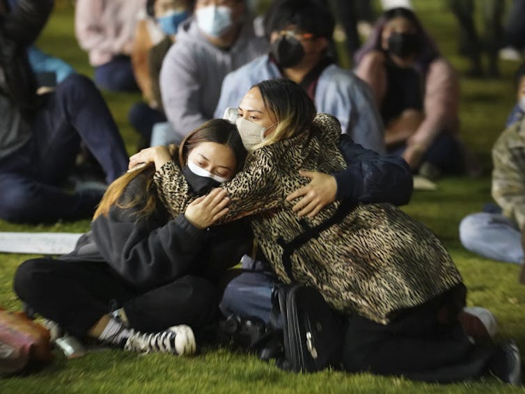 Group of girls sit hugging each other at protest