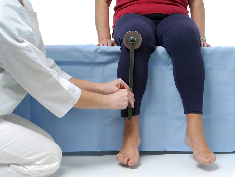 Patient and therapist, measuring the range of movement on a knee joint.