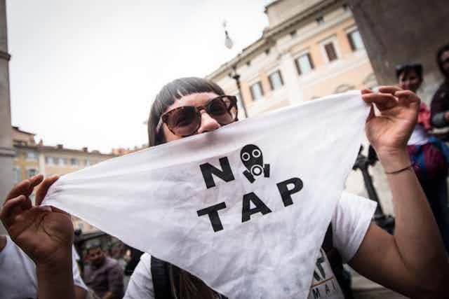 Woman holds sign saying 'no TAP'